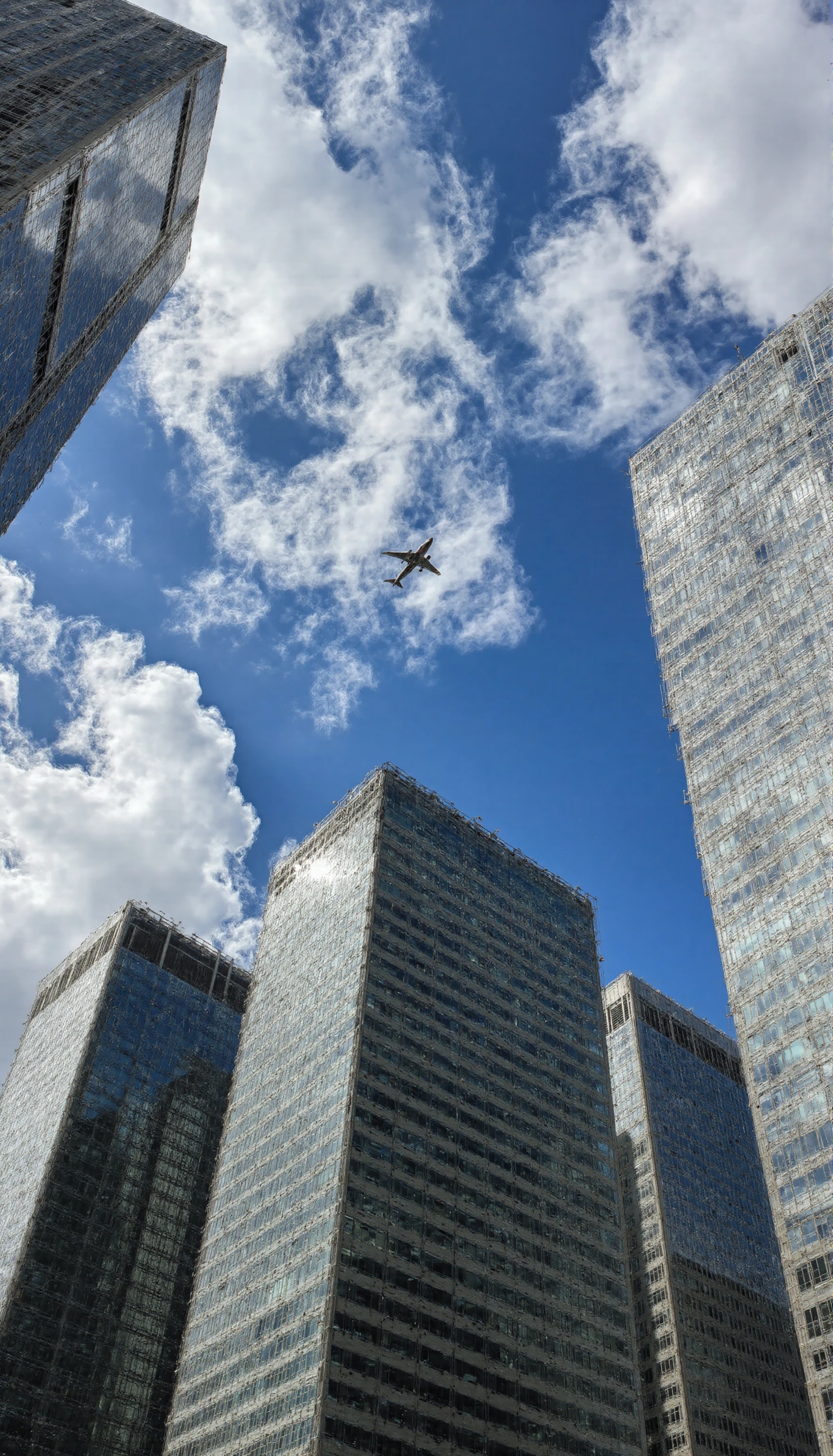 Airplane Soaring Above Modern Glass Skyscrapers Against Blue Sky #41196